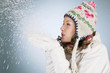 A young woman blowing a handful of snowflakes