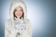 A young woman wearing a winter coat, holding a Christmas present