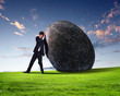 Businessman rolling a giant stone