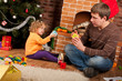 Little girl play with her dad  near Christmas tree