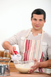 Photo: young man using an electric egg beater young man using an electric egg beater