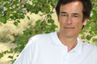 Man smiling in front of tree