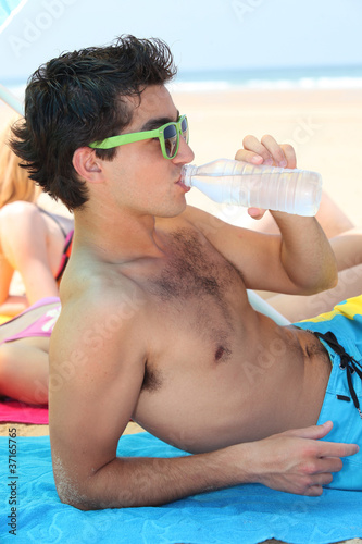 Photo: Teenager drinking water on the beach Teenager drinking water on the beach