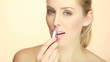 Smiling Glamorous Lady Applying Lipstick in a shade of pink