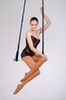 Young woman on trapeze, on white background.
