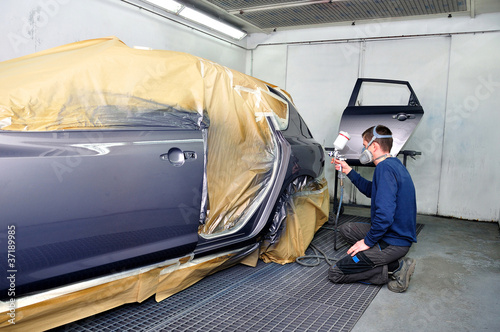 Photo: Worker painting a car. Worker painting a car.