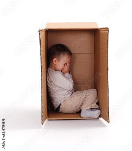 Photo: Sad little boy hiding in cardboard box Sad little boy hiding in cardboard box