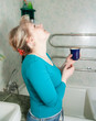 woman with glass of  medicine gargling
