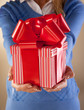 Casually dressed female holding nicely wrapped present.