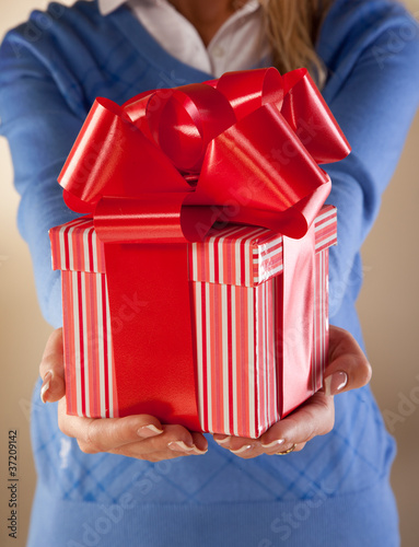 Photo: Casually dressed female holding nicely wrapped present. Casually dressed female holding nicely wrapped present.