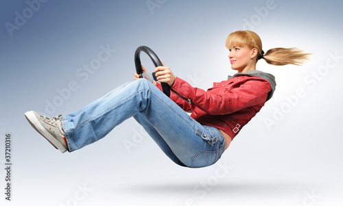 Photo: Young girl car driver in red jacket with a wheel, concept Young girl car driver in red jacket with a wheel, concept