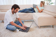 Foto: Woman using a tablet computer while her boyfriend is using a lap Woman using a tablet computer while her boyfriend is using a lap
