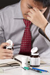 Photo: a stress businessman hold a bottle of pill act headache. a stress businessman hold a bottle of pill act headache.