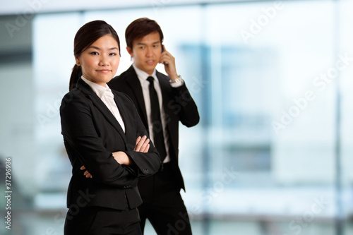 Photo: Asian Business woman with colleague in background Asian Business woman with colleague in background