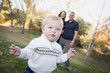 Cute Young Boy Walking as Parents Look On From Behind
