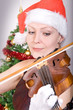 Young woman playing the viola before the Christmas tree.. Young woman playing the viola before the Christmas tree..