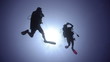 Silhouette view of two adult scuba divers.