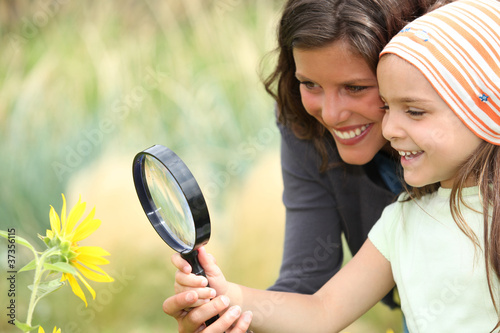 Photo: Mother and daughter examining a flower using a magnifying glass Mother and daughter examining a flower using a magnifying glass