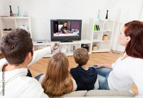 Foto: Young family watching TV at home Young family watching TV at home