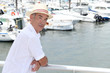 Older man in a straw panama hat standing by a marina