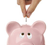 Male hand putting coin into a piggy bank isolated on white