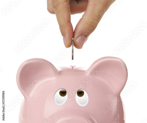 Photo: Male hand putting coin into a piggy bank isolated on white Male hand putting coin into a piggy bank isolated on white