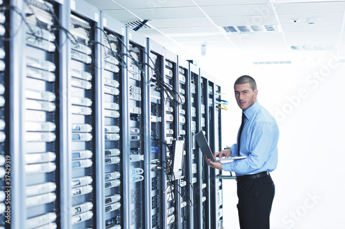 Photo: businessman with laptop in network server room businessman with laptop in network server room