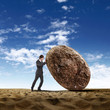 Businessman rolling a giant stone