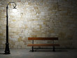 Illuminated brick wall with old fashioned street light and bench