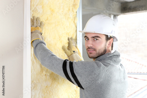 Photo: Worker installing new insulation Worker installing new insulation