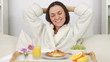 Young happy woman in bed with breakfast stretching and yawning