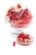 Photo: Pomegranate cut and open in a glass bowl, isolated on white Pomegranate cut and open in a glass bowl, isolated on white
