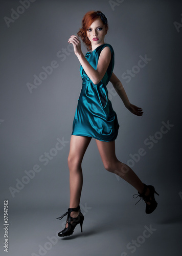 Photo: Healthy young active redhead girl running in blue dress Healthy young active redhead girl running in blue dress