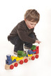 Photo: cute little boy playing with colorful wooden train cute little boy playing with colorful wooden train