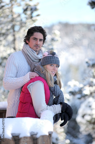 Photo: Young couple leaning out of their ski cabin Young couple leaning out of their ski cabin