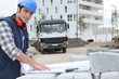 Foto: young foreman outdoors with plan amid cobblestones young foreman outdoors with plan amid cobblestones