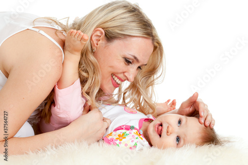 Photo: Loving mother plaing with her baby; child is lying on sheepskin Loving mother plaing with her baby; child is lying on sheepskin