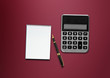 calculator, a pen and blank paper on the table