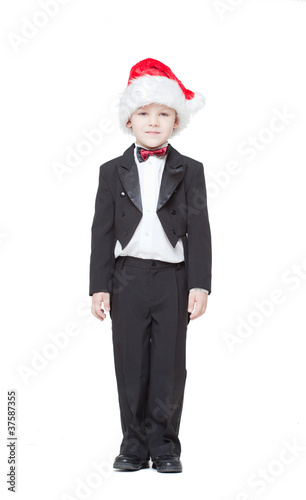 Photo: boy in a tuxedo and a cap Santa Claus on a white background boy in a tuxedo and a cap Santa Claus on a white background