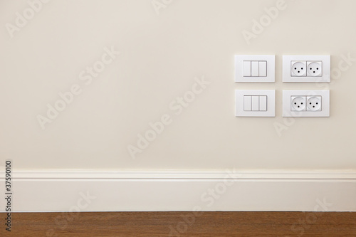 Photo: Power outlet and light switch on the wall Power outlet and light switch on the wall