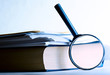 A pile of paper and a book through the magnifying glass