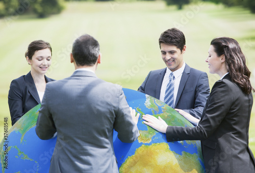 Photo: Business people standing outdoors with large ball Business people standing outdoors with large ball