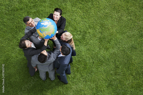 Photo: Business people lifting globe together outdoors Business people lifting globe together outdoors