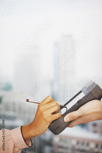 Photo: Woman writing signature on electronic device Woman writing signature on electronic device