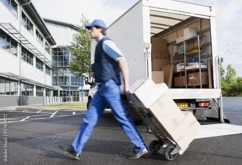 Photo: Deliveryman puling boxes on hand truck Deliveryman puling boxes on hand truck