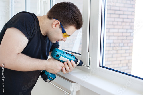 Photo: Man worker mounting window Man worker mounting window