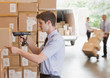Businessman using scanner on box in warehouse