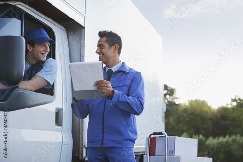 Photo: Deliveryman talking with worker holding clipboard Deliveryman talking with worker holding clipboard
