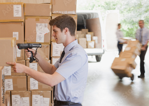 Photo: Businessman using scanner on box in warehouse Businessman using scanner on box in warehouse