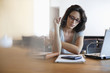 Photo: Woman sitting at desk looking at notebook Woman sitting at desk looking at notebook